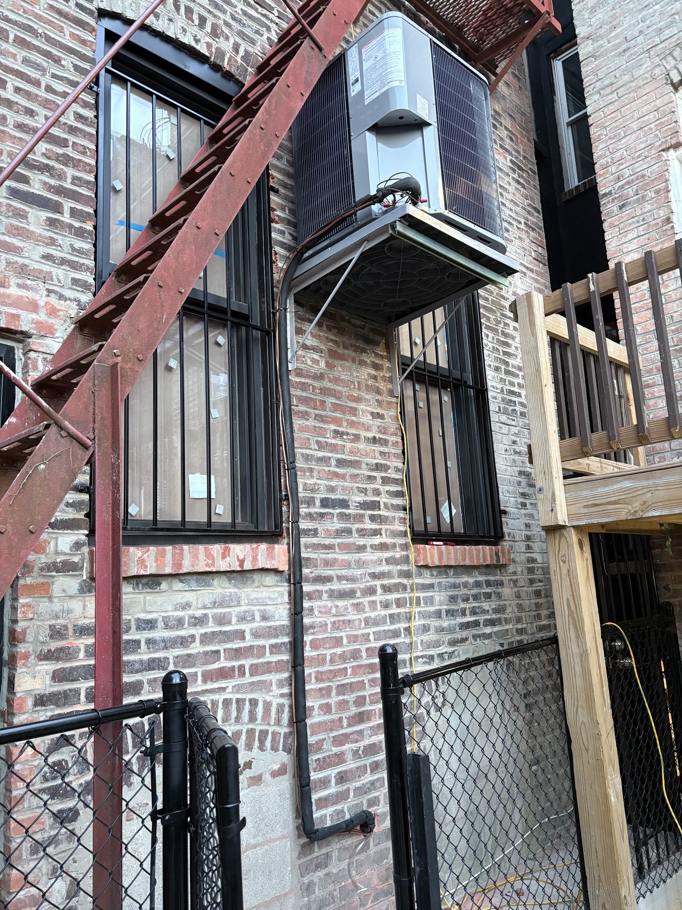Wall-mounted outdoor condenser unit on a brick building
